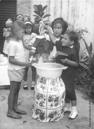 Um botijão de gás coberto, uma bacia com água em cima e estava pronto o “altar” para o batizado das bonecas das meninas.